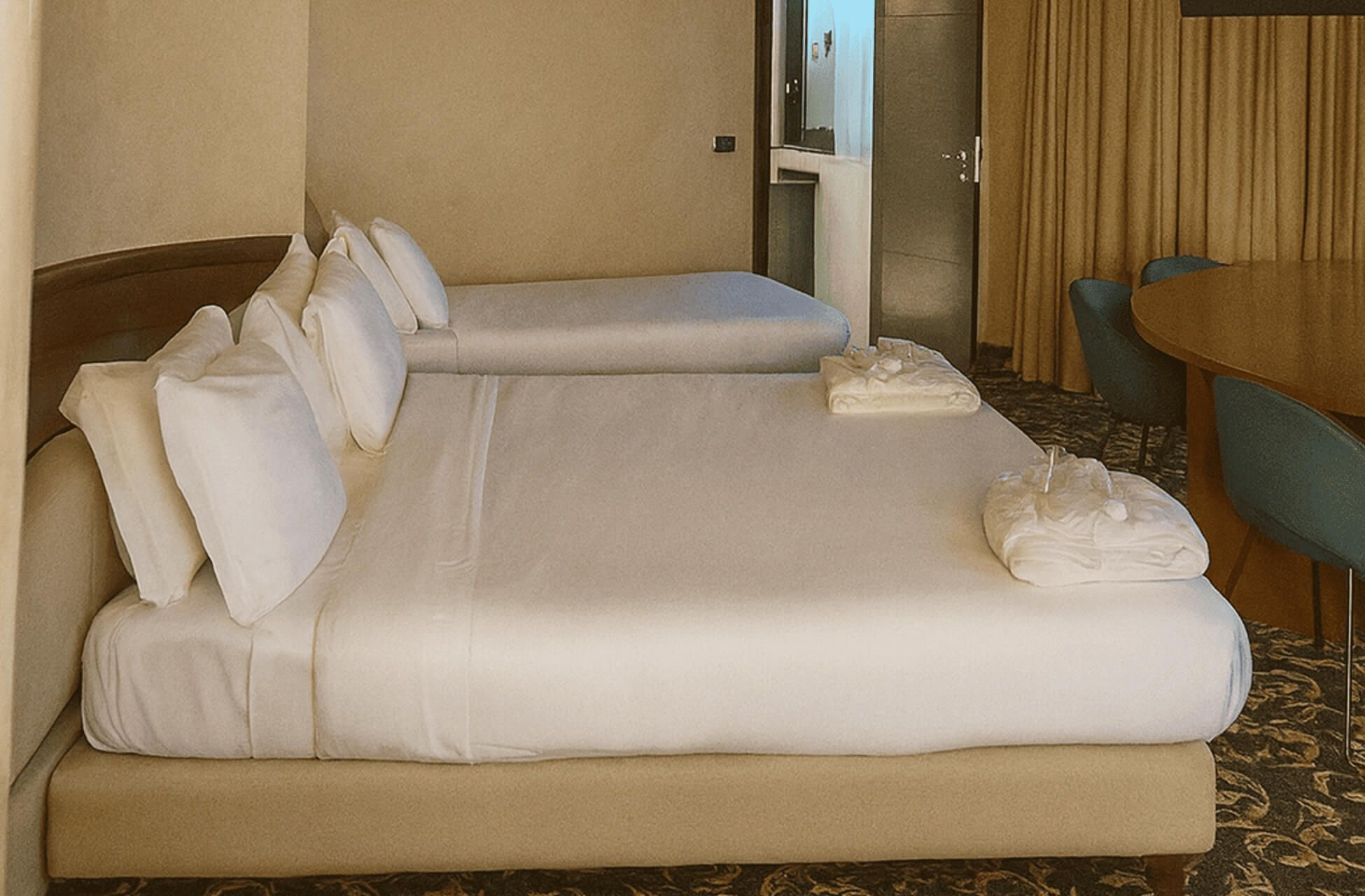 Camera ampia con due letti, moquette scura decorata e accesso visibile al bagno illuminato.