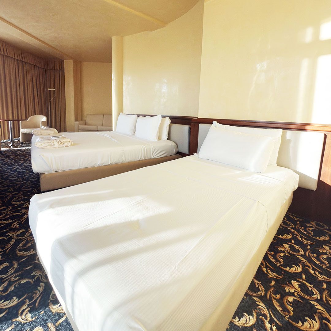 Ampia suite di Hotel con due letti singolo e matrimoniale, moquette decorata.