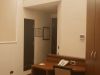 Ingresso di suite junior d’hotel con scrivania in legno, sedia, telefono fisso, armadio a tutta altezza e porte interne sullo sfondo